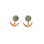 A pair of earrings featuring a crescent moon design with a stone in the center, attached to a gold-colored backing. Available at Be Charmed