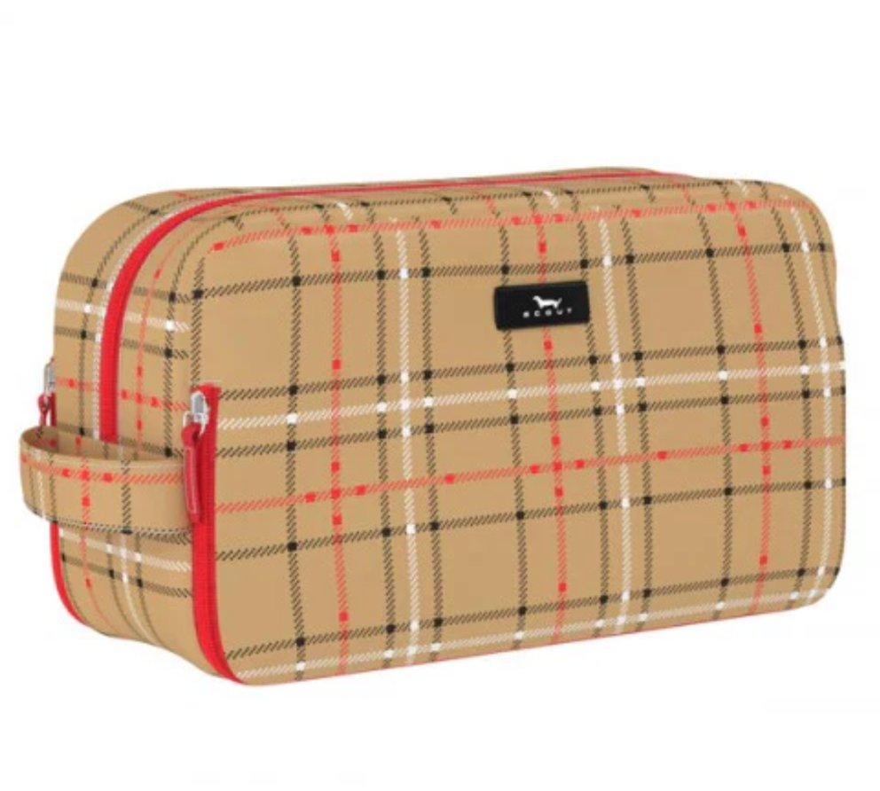 A rectangular toiletry bag with a beige plaid pattern, featuring red and black stripes, a top zipper, a side loop handle, and a small black brand patch on the front. Available at Be Charmed