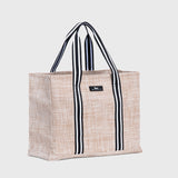 Sand woven Scout tote bag with black and white striped handles on a light gray background. Available at Be Charmed