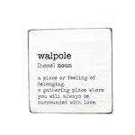 A decorative wooden block with the text 'WALPOLE a place or feeling of belonging, a gathering place where you will always be surrounded by love.' on it, with a definition of 'Homeless' written at the top. Available at Be Charmed
