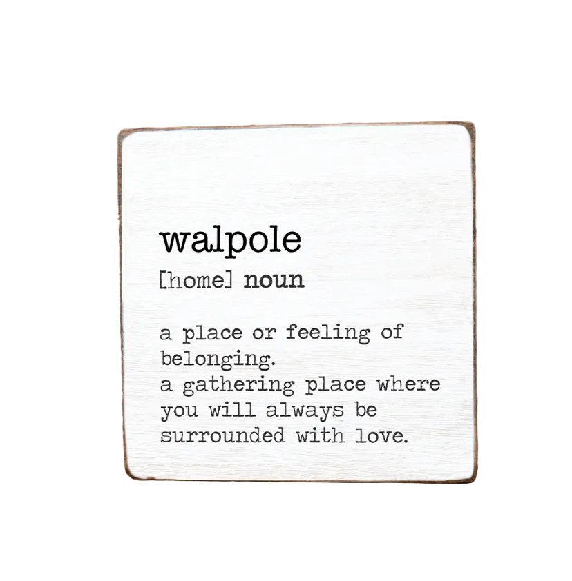 A decorative wooden block with the text 'WALPOLE a place or feeling of belonging, a gathering place where you will always be surrounded by love.' on it, with a definition of 'Homeless' written at the top. Available at Be Charmed