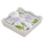 Floral napkins with a white ribbon in a decorative white holder on a white background. Available at Be Charmed