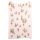 The Darling Effect throw blanket with winter scene pattern featuring trees and skiers on a white background. Available at Be Charmed. 