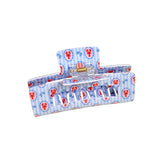 Blue hair clip with red lobster pattern on a beige background. Available at Be Charmed
