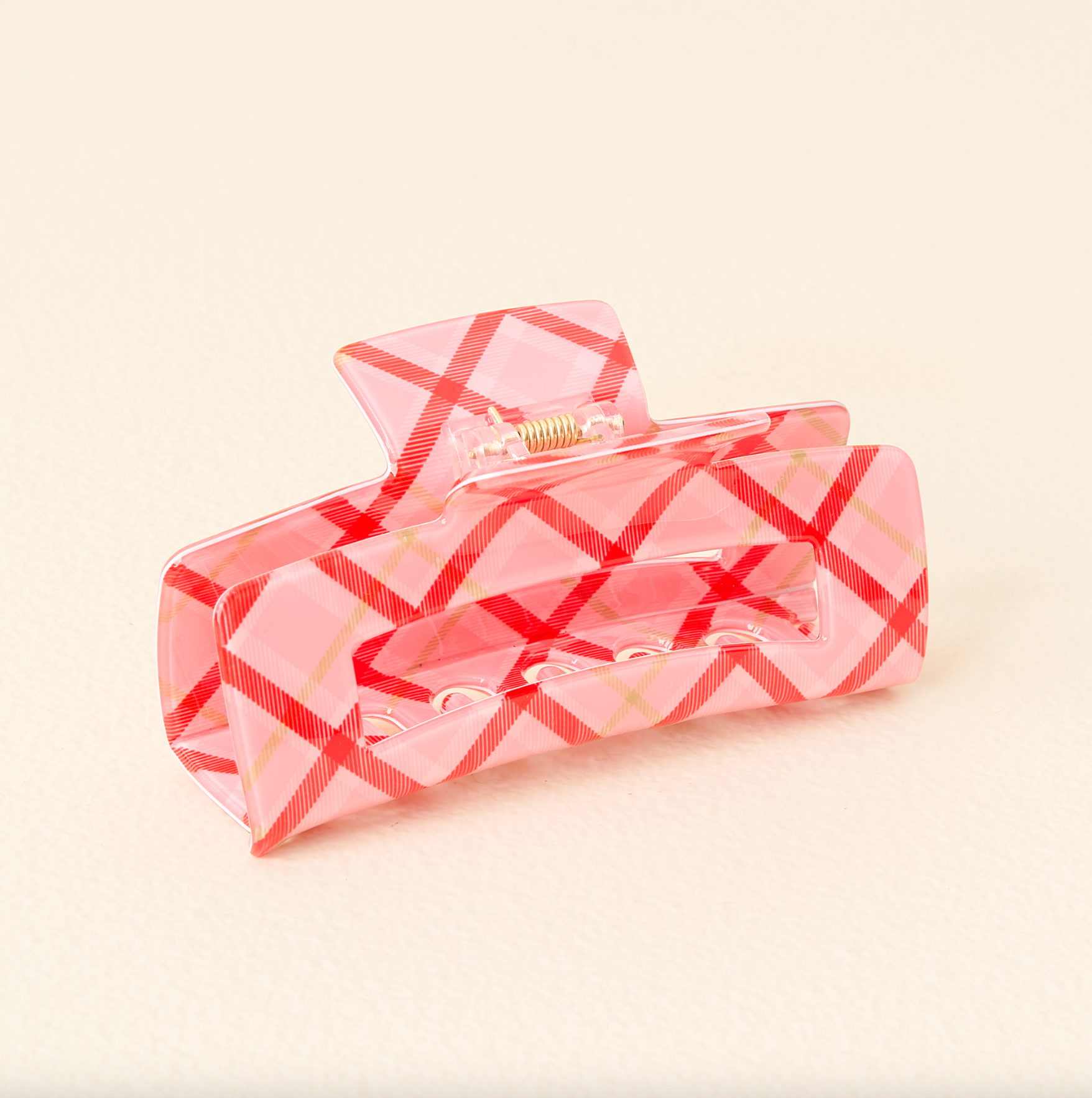 The darling effect pink checkered hair claw clip on a beige background. Available at Be charmed.