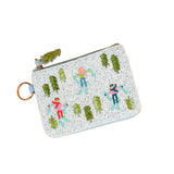 A small zippered Darling Effect pouch with a light blue border and a gold-tone key ring, decorated with embroidered figures and trees in green, pink, blue, and orange on a speckled white fabric. Available at Be Charmed