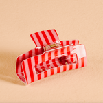 Red and white striped the darling effect hair clip on a beige background. Available at Be Charmed. 