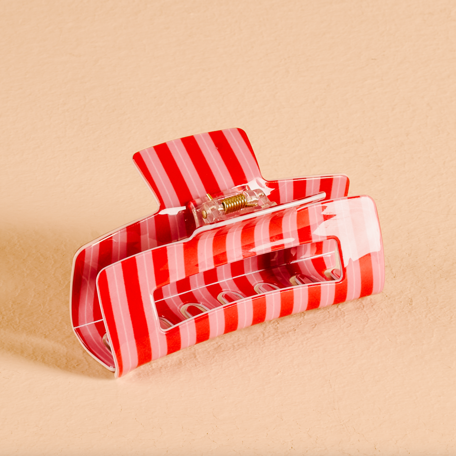 Red and white striped the darling effect hair clip on a beige background. Available at Be Charmed. 