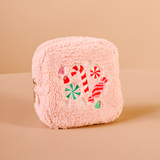 Pink fluffy cosmetic pouch with candy-themed design on a beige background. Available at Be Charmed.