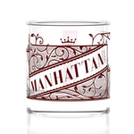 Clear glass tumbler with red 'Manhattan' design on a white background. Available at Be Charme