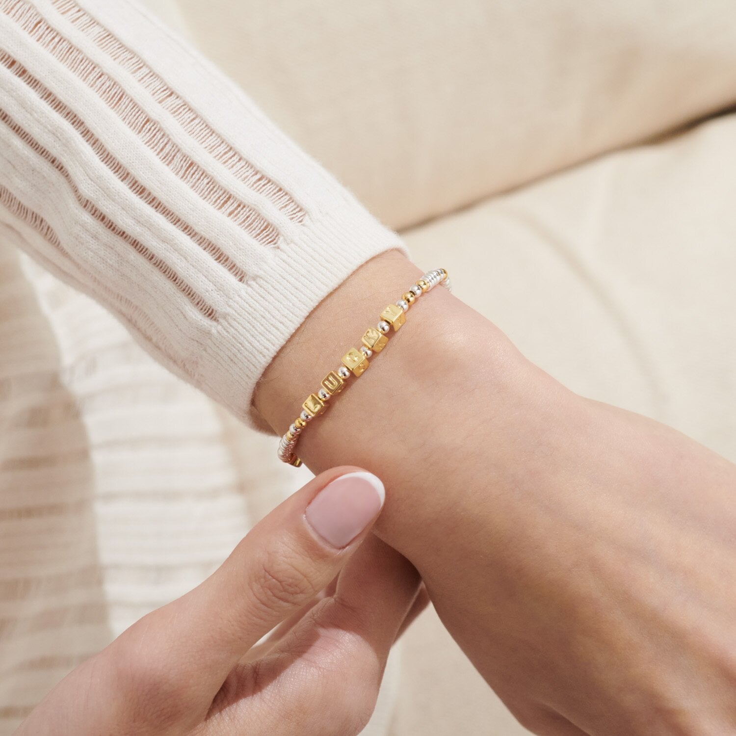 Gold bracelet on a wrist with a neutral background. Available at Be Charmed