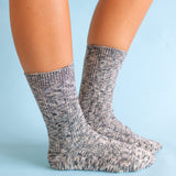 Gray marbled world softest cable crew socks worn by a person on a light blue background. available at Be charmed