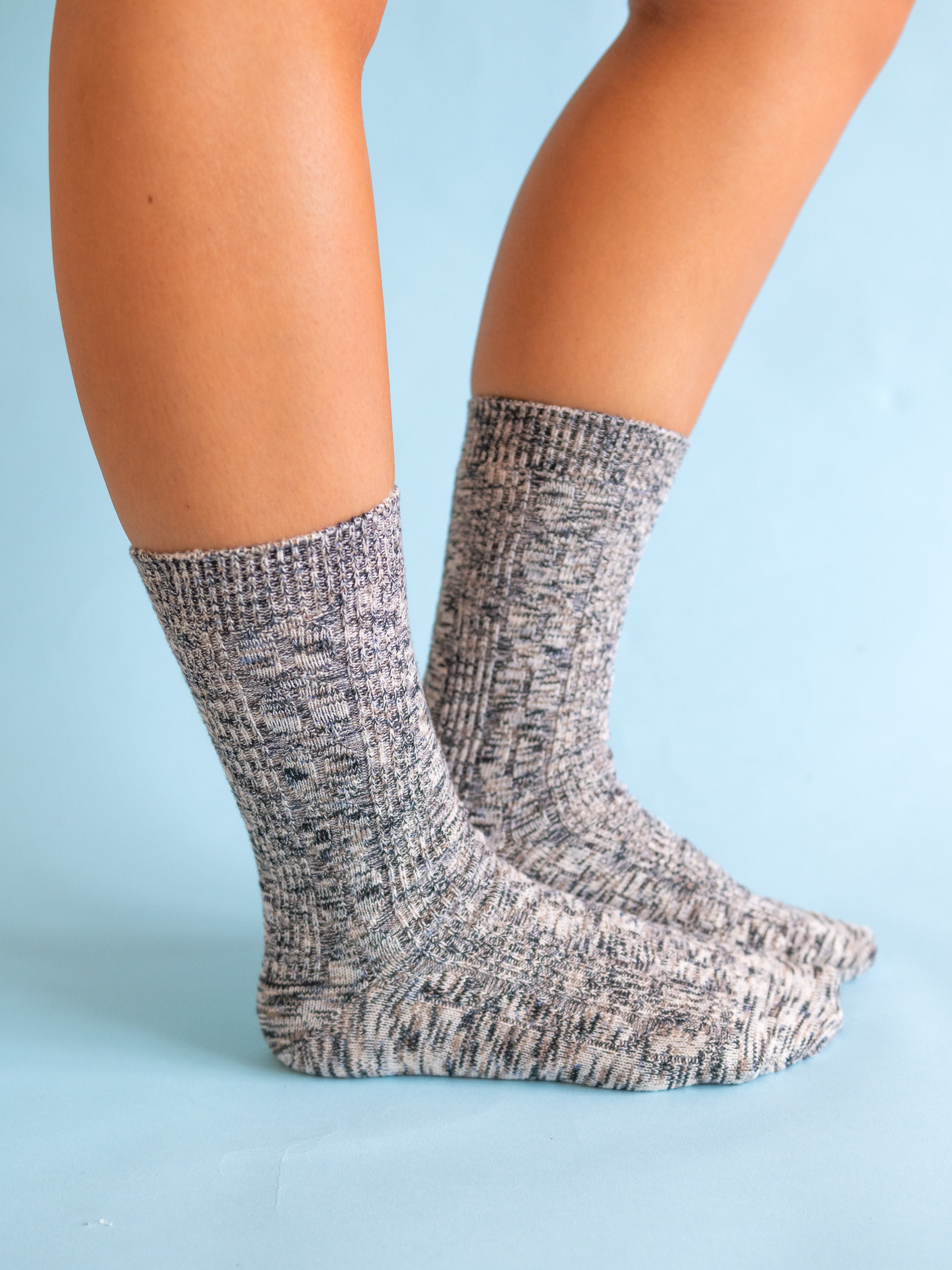 Gray marbled world softest cable crew socks worn by a person on a light blue background. available at Be charmed