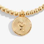 Gold beaded bracelet with a heart-shaped charm on a light background. Available at Be Charmed
